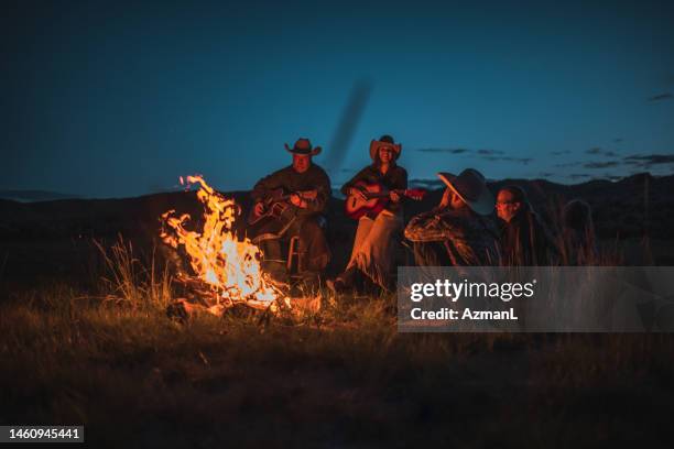 western family sharing music and stories next to a campfire - country and western music stockfoto's en -beelden