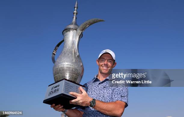 Rory McIlroy of Northern Ireland poses with the trophy on the 18th green following victory in the final round of the Hero Dubai Desert Classic at...