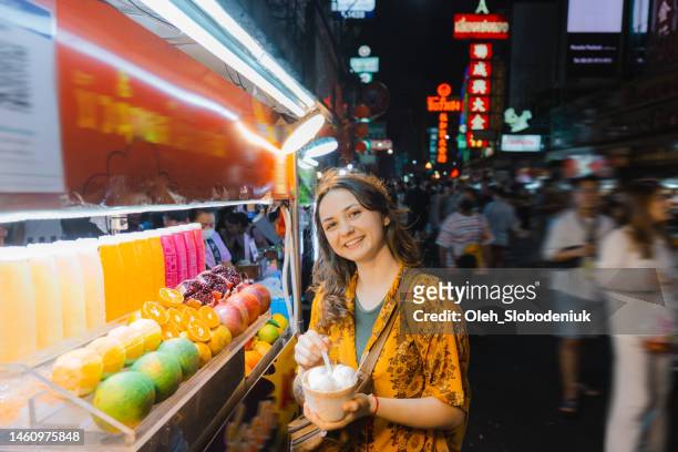 frau isst kokosnusseis auf nachtmarkt in chinatown, bangkok - thai food stock-fotos und bilder