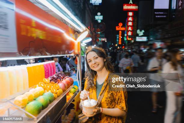 woman eating coconut ice cream on night market in chinatown, bangkok - street food market stock pictures, royalty-free photos & images