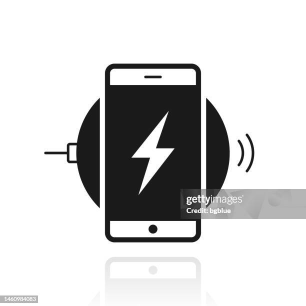 smartphone charging on wireless charger. icon with reflection on white background - wireless charging stock illustrations