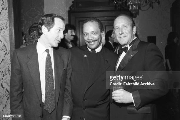 Quincy Jones standing with Clive Davis and Mort Zuckerman attending Davis's legendary pre-grammy party at the Helmsley Palace on March 2, 1988 in New...