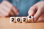 Hand flipping of 2023 to 2024 on wooden block cube for preparation new year change and start new business target strategy concept.