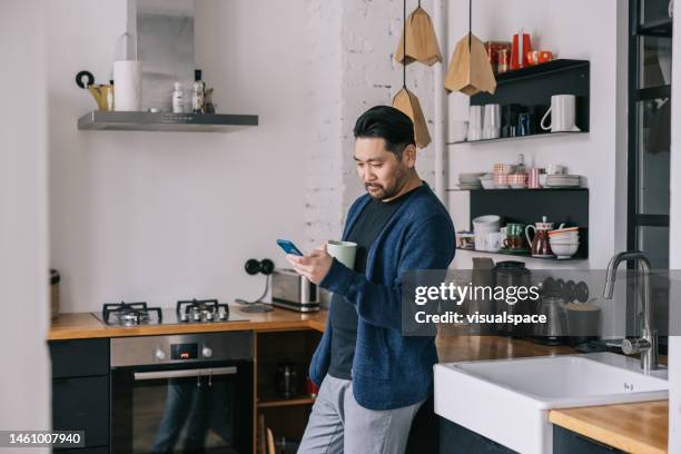 japanese man having a cup of coffee at home - estland stockfoto's en -beelden