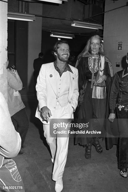 Actor Jack Nicholson wearing a white three-piece suit, followed by model Veruschka at a rally for Senator George McGovern at Madison Square Garden in...