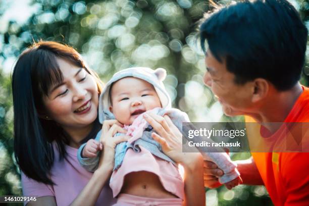 mother and father playing with baby outdoors - korean people stock pictures, royalty-free photos & images