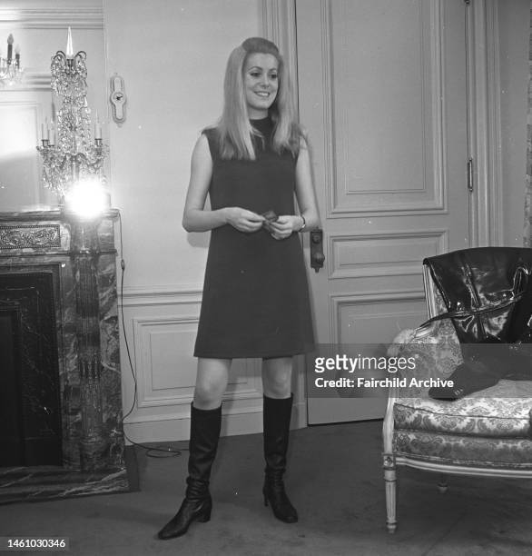 French actress Catherine Deneuve wearing minidress and knee-high leather boots