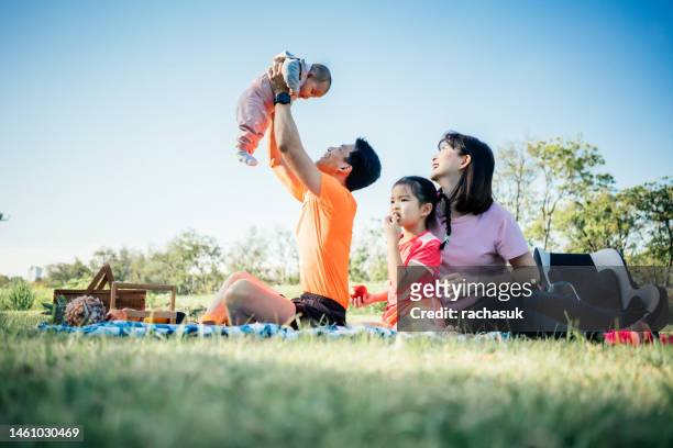 familie entspannt und spielt im öffentlichen park - asian young family stock-fotos und bilder
