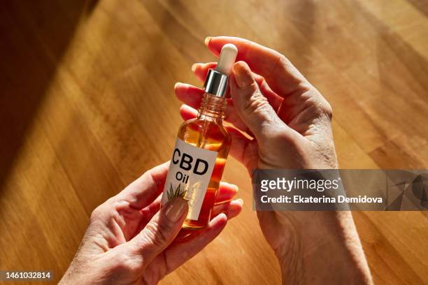 crop person demonstrating bottle of cbd oil - cannabis oil - fotografias e filmes do acervo
