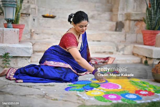 indian woman in a sari making rangoli on floor - kolam stockfoto's en -beelden