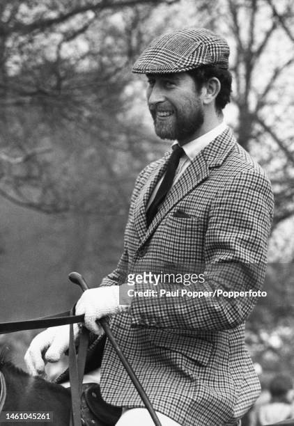 Sporting a beard and wearing a checked jacket and cap, Prince Charles watches a cross country event from horseback at Badminton Horse Trials in...