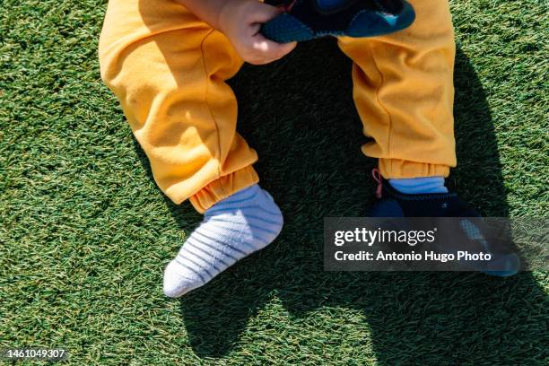 boy removing a shoe from one foot - baby boot stock pictures, royalty-free photos & images