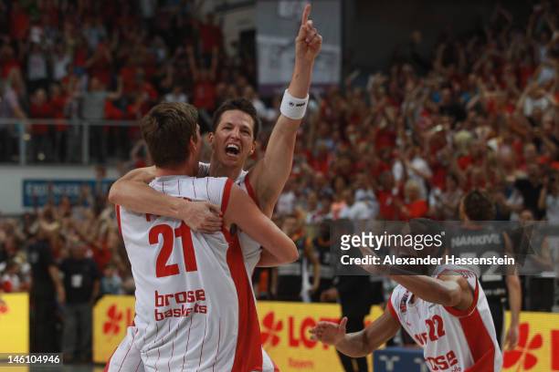 Tibor Pleiss of Bamberg celebrates victory with his team mate Casey Jacobsen and Brian Roberts after winning game 3 of the Beko BBL finals between...