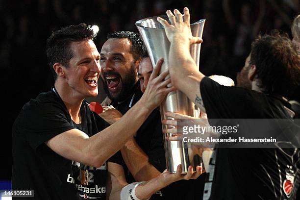 Casey Jacobsen of Bamberg presents the Champions Trophy to his team mates after winning game 3 of the Beko BBL finals between Brose Baskets and...