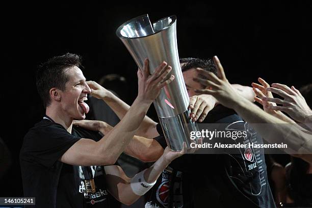 Casey Jacobsen of Bamberg presents the Champions Trophy to his team mates after winning game 3 of the Beko BBL finals between Brose Baskets and...