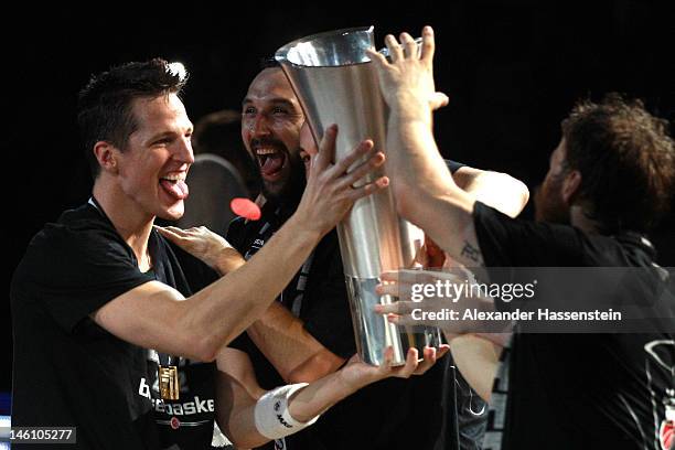 Casey Jacobsen of Bamberg presents the Champions Trophy to his team mates Predrag Surup and Anton Gavel after winning game 3 of the Beko BBL finals...