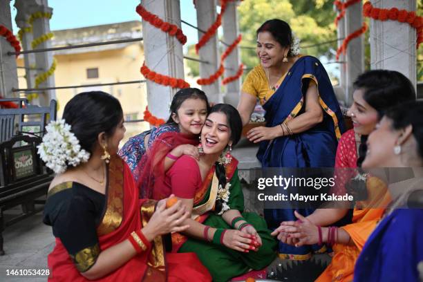 cute girl embraces her mother while she makes ladoos - diwali family stock pictures, royalty-free photos & images