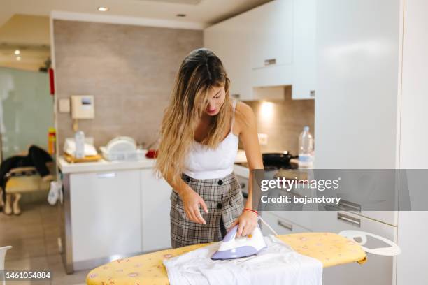 beautiful young woman is ironing clothes at home - ironing stock pictures, royalty-free photos & images