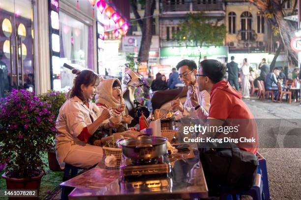 asiatische chinesische familie genießt street food auf dem nachtmarkt hanoi vietnam - vietnam teen stock-fotos und bilder