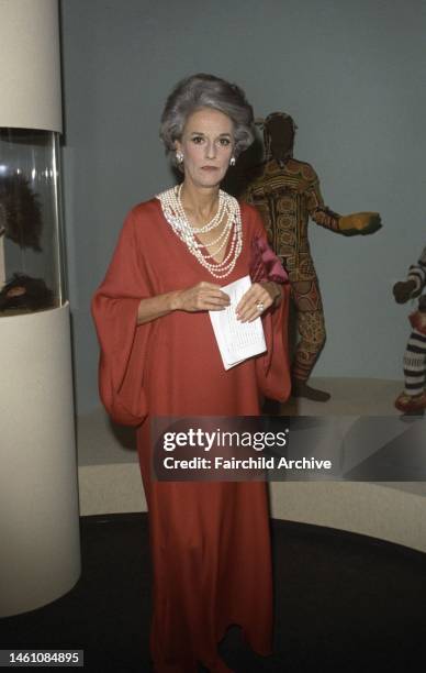 Babe Paley wearing a pink silk dress with a pearl necklace at the opening of the Museum of Modern Art's African Textiles and Decorative Arts exhibit...