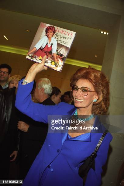 Sophia Loren holds up her second cook book 'Sophia Loren's Recipes and Memories' during her book signing at the Armani Flagship store on Madison...