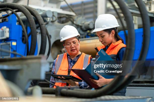 thank you for this great opportunity to be your colleague. senior adult engineer explaining machine functioning to new engineer and how to operate an injection molding machine. plastic manufacturing industry. - werk in uitvoering stockfoto's en -beelden