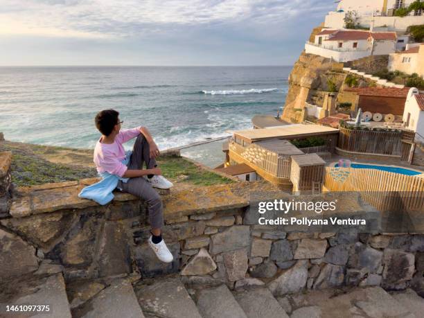 boy looking at the view from azenha do mar - cliff wall stock pictures, royalty-free photos & images