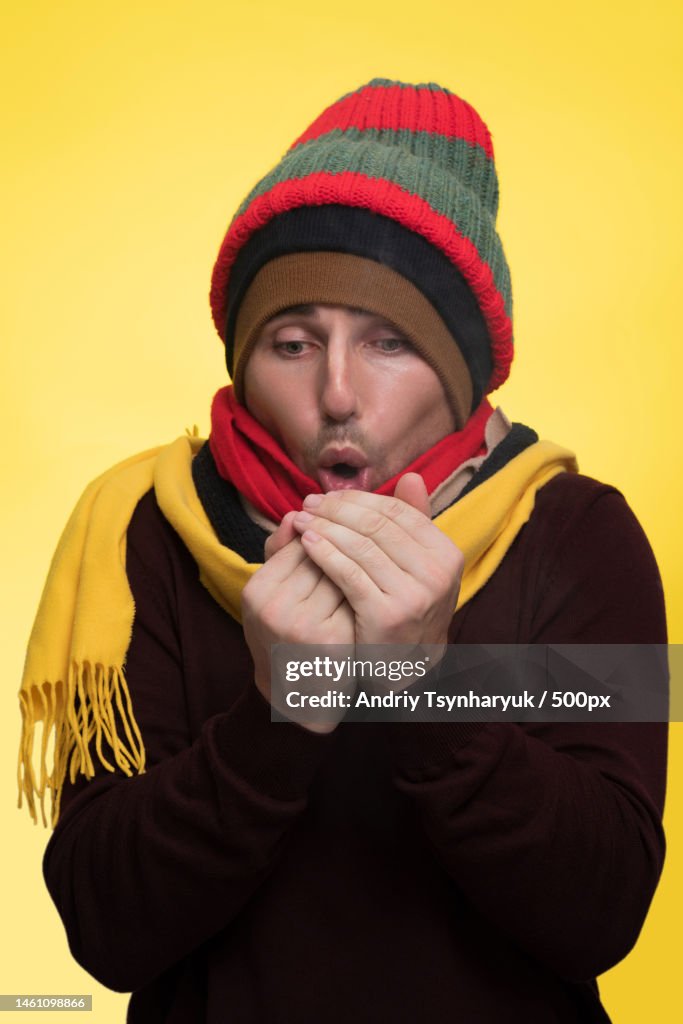 Shameful african american pulling a green winter hat over his face He