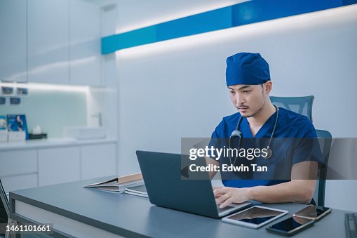 Asian Chinese Doctor working in Doctor's office typing with laptop Asian Chinese Doctor working in Doctor's office typing with laptop