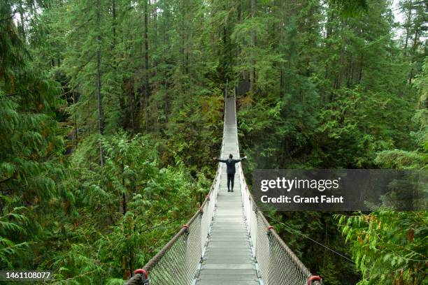 young woman on suspension bridge - vancouver bridge stock pictures, royalty-free photos & images
