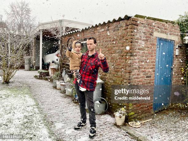 father with toddler son in snow - holland achtertuin stockfoto's en -beelden