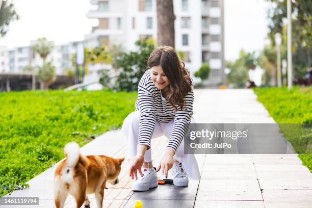 young woman walking in park with her shiba inu dog - shiba inu adult stock pictures, royalty-free photos & images