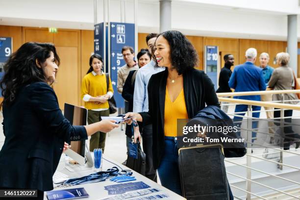 receptionist giving participant id to business conference attendee - geschäftskonferenz stock-fotos und bilder