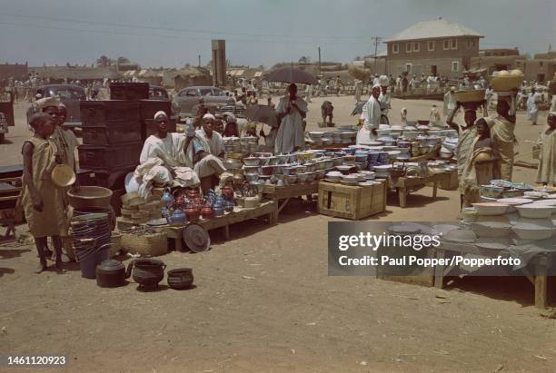 Stallholders sell pots, pans, kettles and crockery to customers at a busy street market in Kano, capital city of Kano State in northern Nigeria circa...