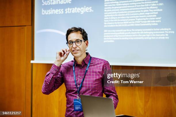 businessman talking into headset while giving presentation at conference - business conference stock pictures, royalty-free photos & images