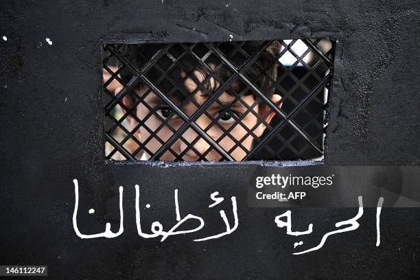 Bahraini Shiite Muslim boy holds a placard depicting prison bars and reading in Arabic, "Freedom for our children" during a protest in solidarity...