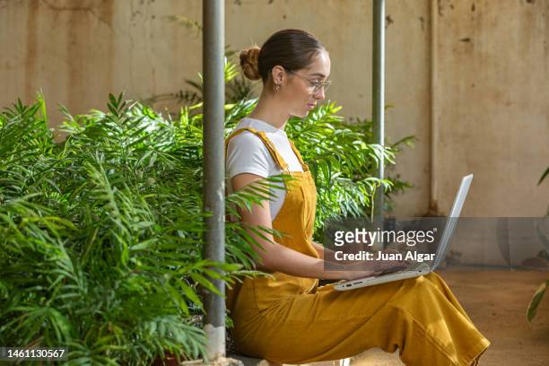 young woman surfing laptop in glasshouse - laptop netbook stock pictures, royalty-free photos & images