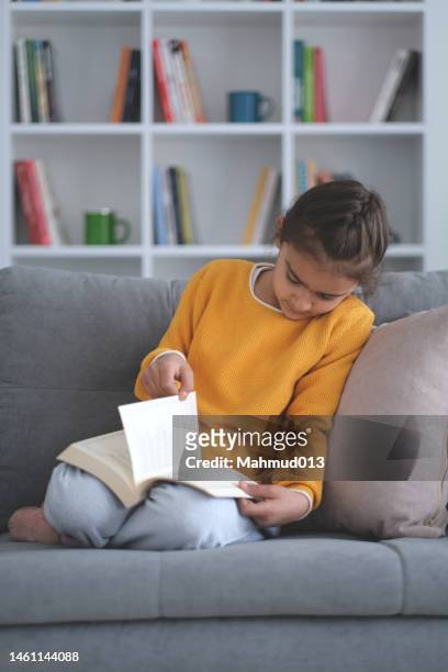 little girl reading the book on sofa - love books stock pictures, royalty-free photos & images