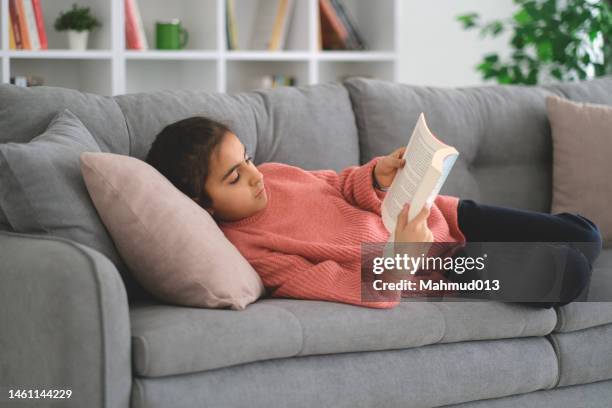 little girl reading the book on sofa - love books stock pictures, royalty-free photos & images