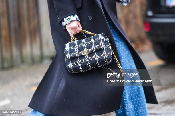 Darja Barannik wears a black t-shirt, a black wool long coat, a black and white checkered print pattern tweed jacket from Chanel, a black wool long...