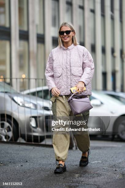 Guest wears black sunglasses, a pale purple quilted pattern jacket, khaki and green yoke pattern large cargo pants, a purple shiny leather Puzzle...