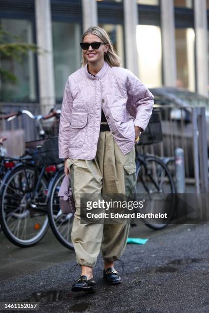 Guest wears black sunglasses, a pale purple quilted pattern jacket, khaki and green yoke pattern large cargo pants, a purple shiny leather Puzzle...