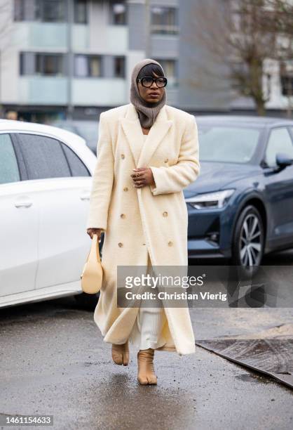 Loicka Grace wears balaclava, beige wool coat, ankle boots, beige bag outside Aeron during the Copenhagen Fashion Week Autumn/Winter 2023 on January...