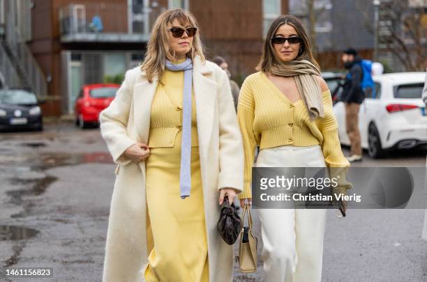 Elise Bak wears creme white coat, yellow dress, fur moon boots, grey scarf & Benthe Liem wears beige cardigan, creme white pants, black boots, scarf,...