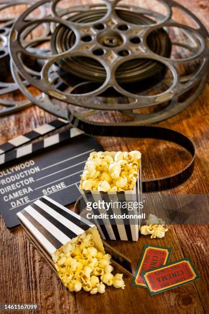 black and white striped bags of popcorn clapboard and movie reels on retro wood background - red carpet movie stock pictures, royalty-free photos & images