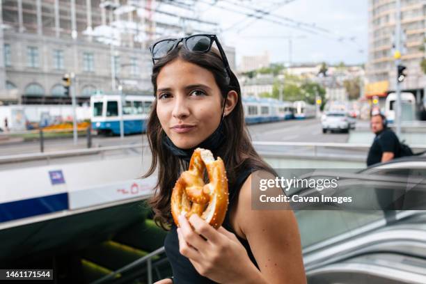 teen girl holds a soft pretzel before going down an escalator - zürich bildbanksfoton och bilder