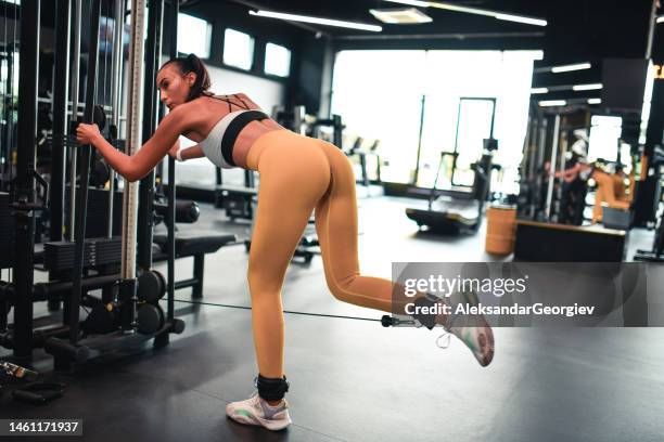 female athlete practicing leg cable kickbacks in gym - curling sport stock pictures, royalty-free photos & images