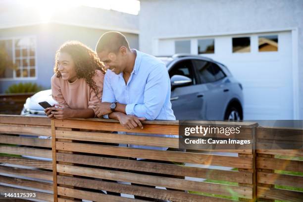 happy heterosexual couple leaning on railing in front yard - generation x stock-fotos und bilder