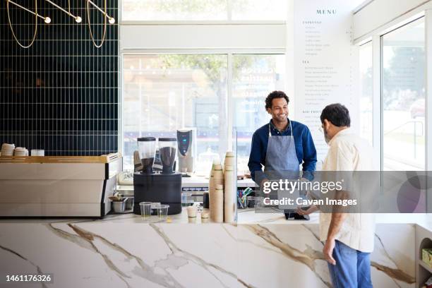 mature customer doing contactless payment at checkout counter in cafe - caixa de balcão imagens e fotografias de stock