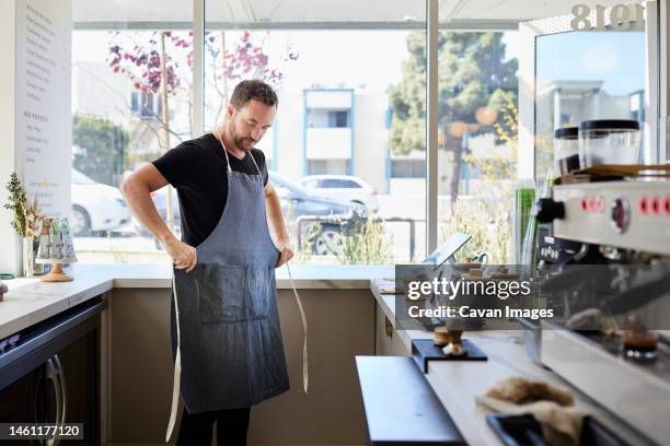 male entrepreneur wearing apron in kitchen at coffee shop - tablier photos et images de collection